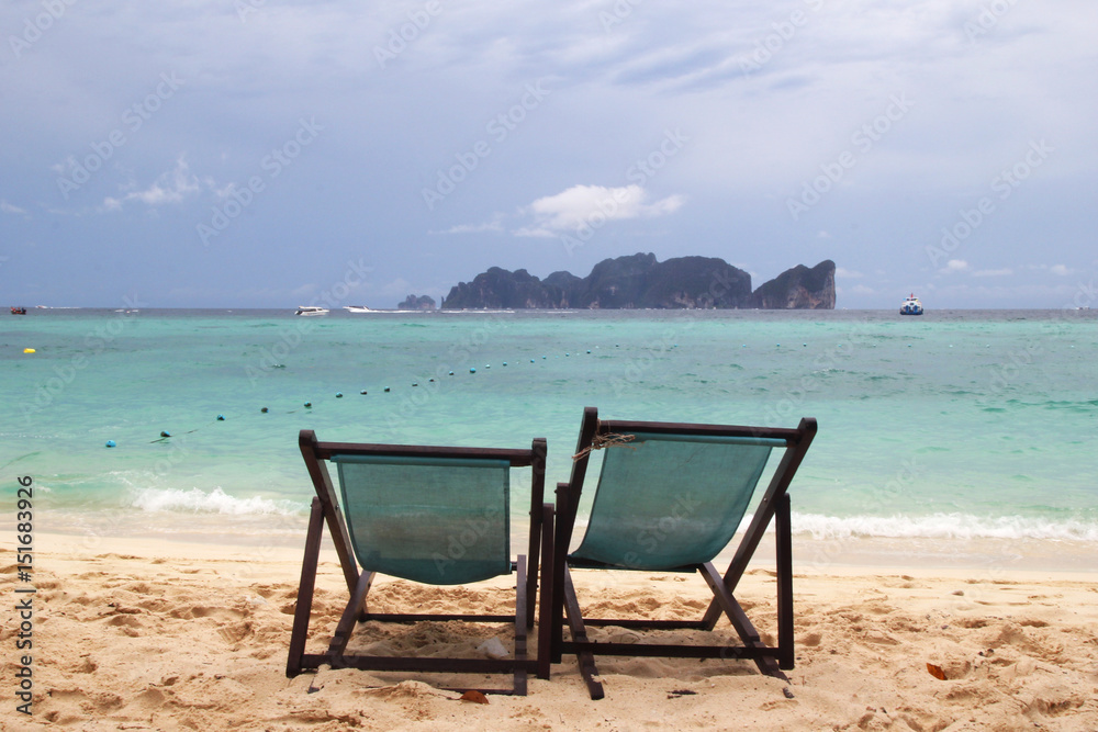 Travel to island Phi Phi, Thailand. Two chairs on a beach near to sea. Travel to island Phi Phi, Thailand. Two chairs on a beach near to sea.
