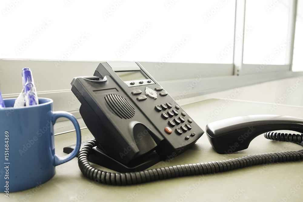 businessman dialing voip phone in the office, keyboard and monitor detail in the background with vintage color tone effect businessman dialing voip phone in the office, keyboard and monitor detail in the background with vintage color tone effect