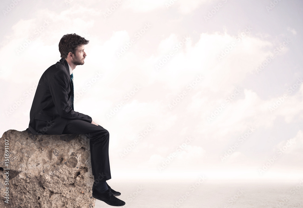 Business man sitting on stone edge Business man sitting on stone edge