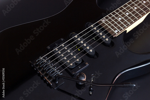 Black electric guitar close up on dark background.