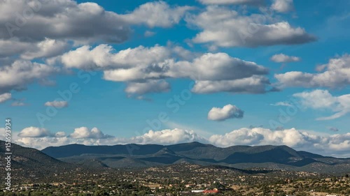 classic fluffy clouds pass over a town and the mountain range