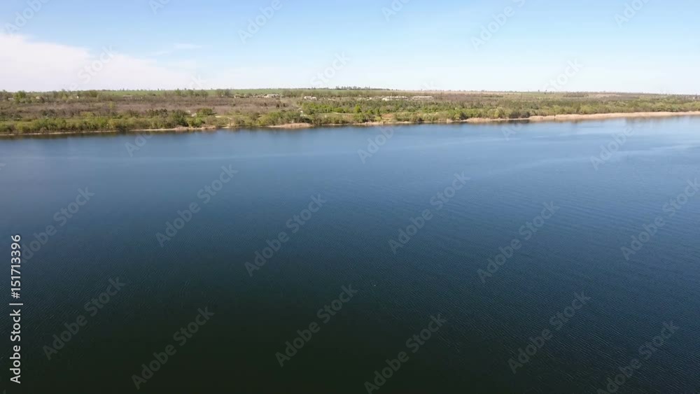 Impressive view on the sparkling blue waters of the Dnipro river and its picturesque riverbank in a sunny day in spring. The skyscape and hirizon look great and gorgeous. Impressive view on the sparkling blue waters of the Dnipro river and its picturesque riverbank in a sunny day in spring. The skyscape and hirizon look great and gorgeous.