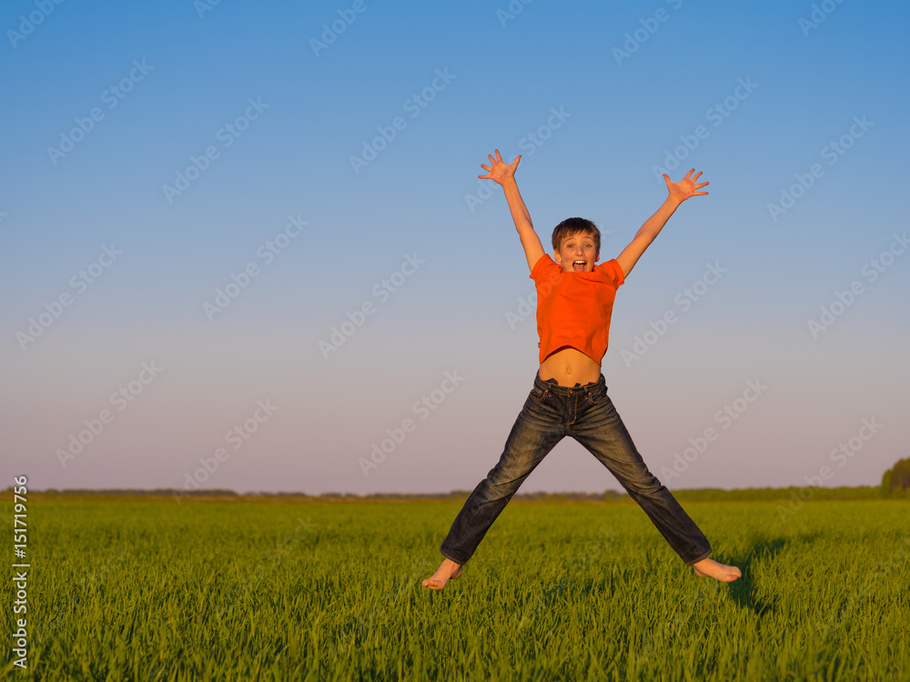 Happy young boy jumping outdoors with raised arms. Happy young boy jumping outdoors with raised arms.