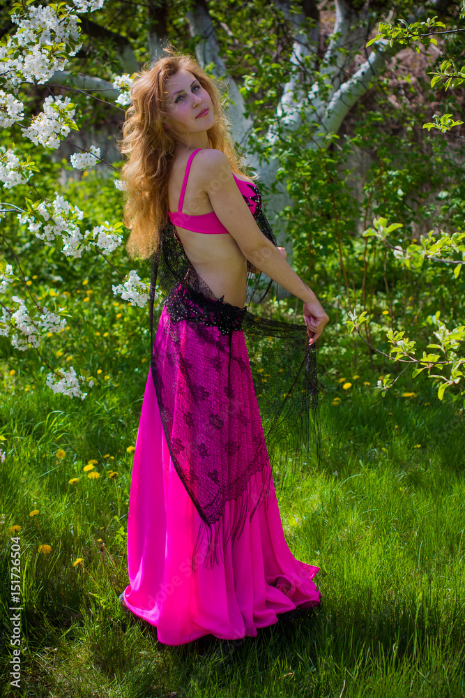 Young pretty blond head woman in Arabic oriental dress fuchsia dress around garden and river in good mood Young pretty blond head woman in Arabic oriental dress fuchsia dress around garden and river in good mood
