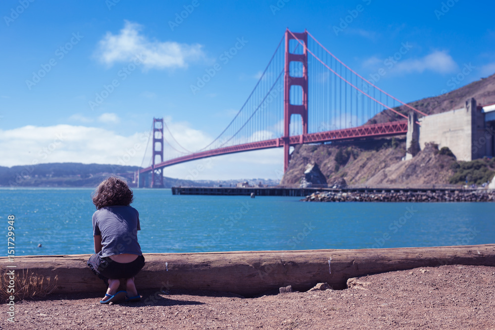 Kid,boy,person tourist sitting, waiting and look forward to theGolden Gate Bridge the iconic landmark of San Francisco Kid,boy,person tourist sitting, waiting and look forward to theGolden Gate Bridge the iconic landmark of San Francisco