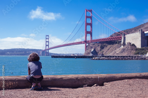 Kid,boy,person tourist sitting, waiting and look forward to theGolden Gate Bridge the iconic landmark of San Francisco