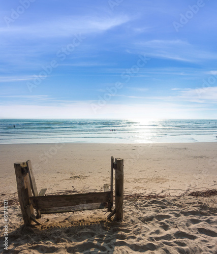 wood bench on sand beach with blue sea and blue sky background