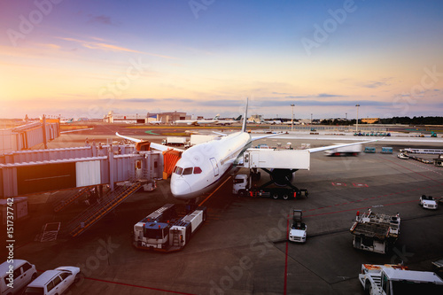 Airplane near the terminal in an airport at the sunset