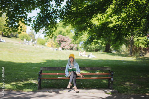 Young woman sat reading her book in the park