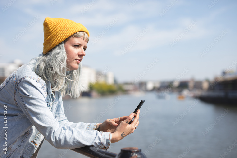 young lady using her phone by the waterfront