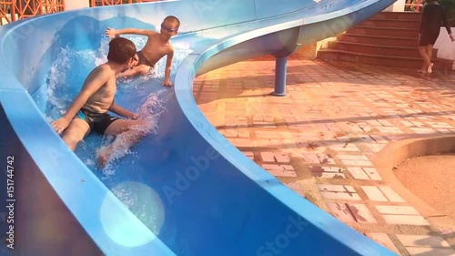 Slow motion from smartphone of two asian Thai boy play water slider in summer.