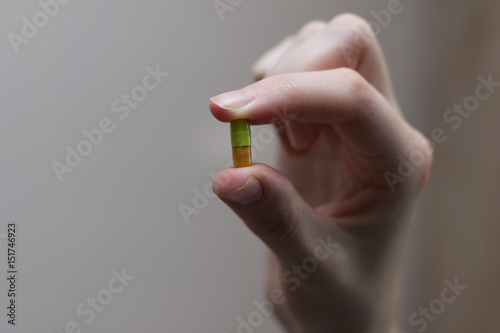Green and orange capsule with medicine in the woman's hand