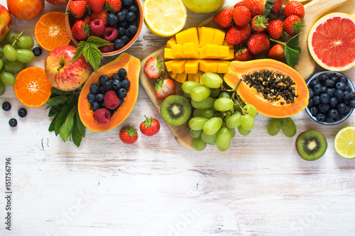 Above view of rainbow colored fruits  strawberries  blueberries  mango  orange  grapefruit  banana  apple  grapes  kiwis on the white background  copy space for text  selective focus