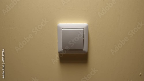 Human hand turn off a power button on a yellow wall