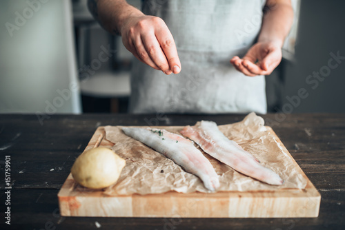 Chef hands salting raw fish over cutting board