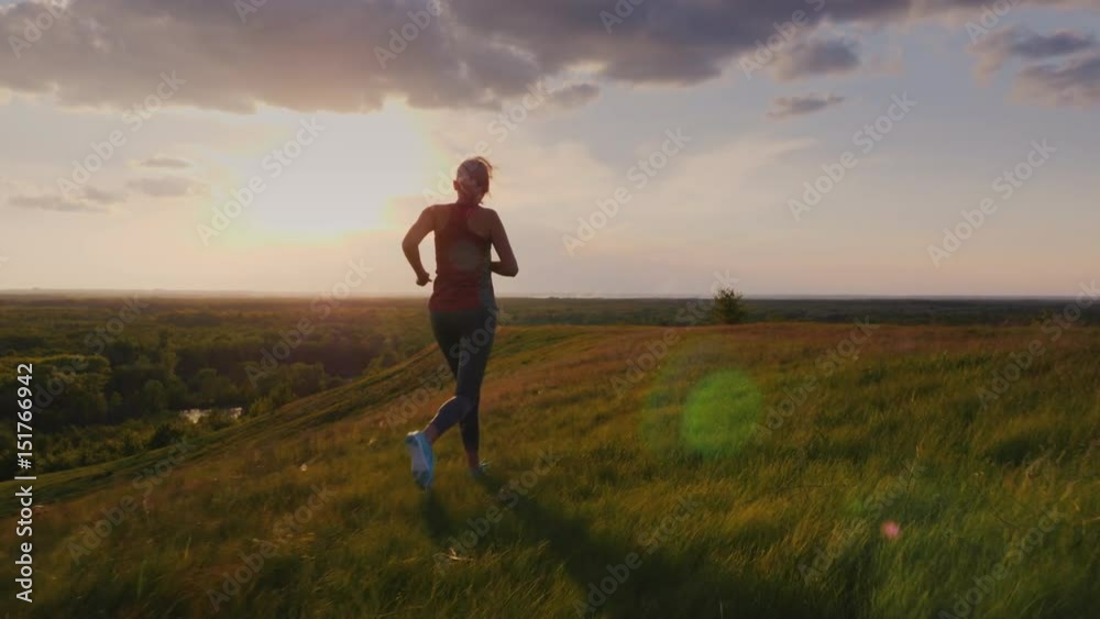 Young woman jogging in a scenic spot at sunset. Back view. 4K slow motion video Young woman jogging in a scenic spot at sunset. Back view. 4K slow motion video