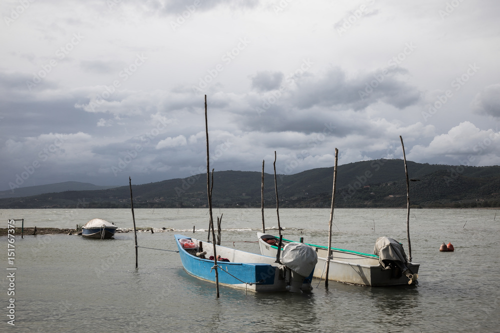 Some small fishing boat on a lake, beneath a cloudy sky Some small fishing boat on a lake, beneath a cloudy sky