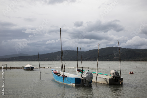 Some small fishing boat on a lake, beneath a cloudy sky