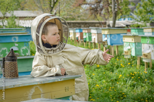 The boy in protective clothing beekeeper works on an apiary. Apiculture.