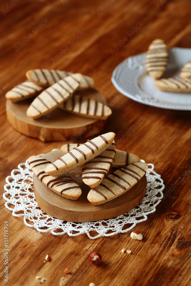 Hazelnut Long Cookies decorated with chocolate treads, on wooden boards, on wooden background.
