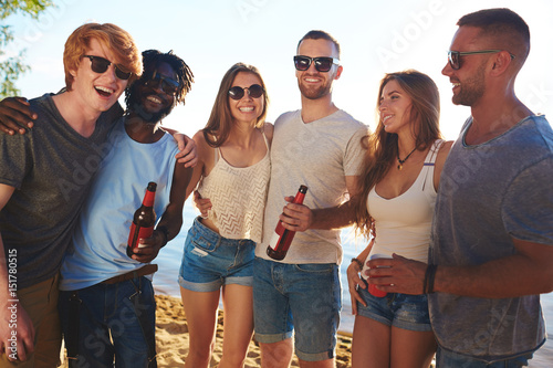 Affectionate buddies with beer enjoying beach party
