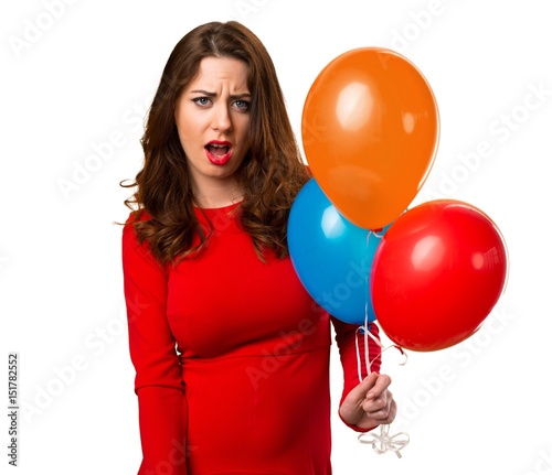 Beautiful young girl holding balloons and making surprise gesture © luismolinero