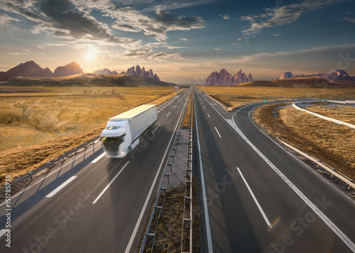 Single white truck on highway at idyllic sunset