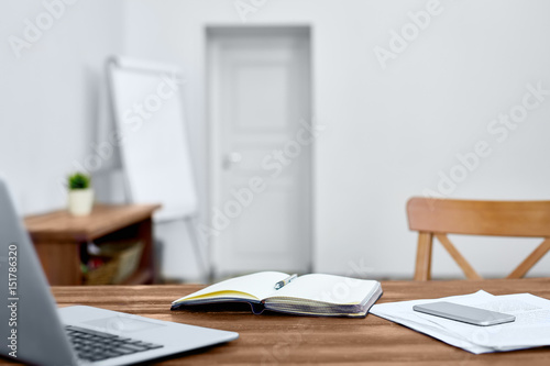 Workplace of modern manager with open notebook, laptop, smartphone and papers