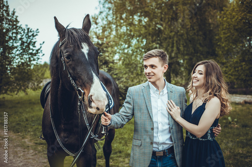 Couple in love walking in the woods with a horse.