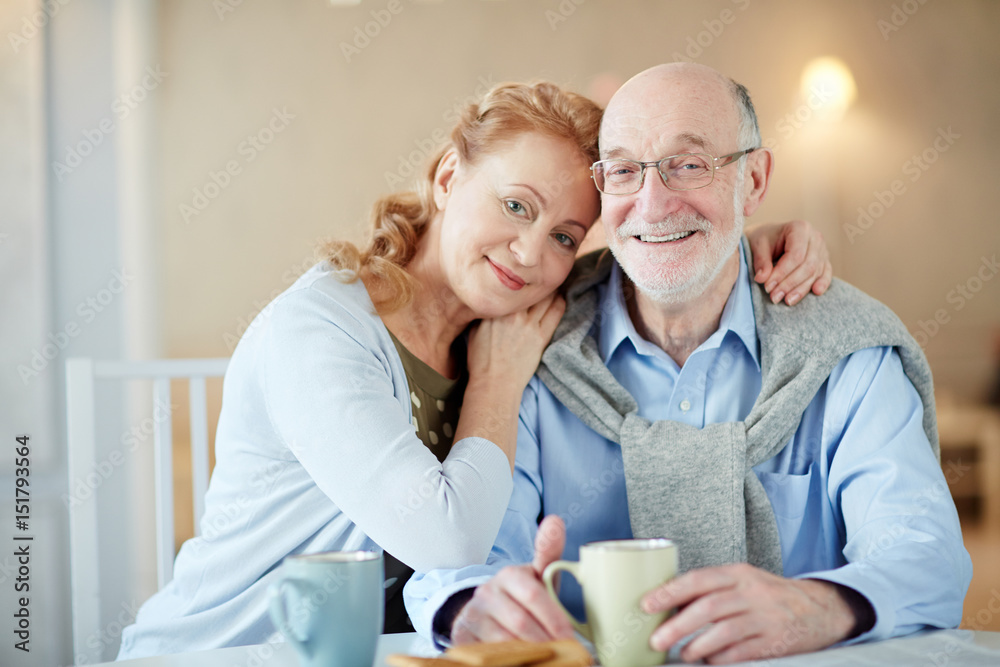 Serene spouses looking at camera by cup of tea Serene spouses looking at camera by cup of tea