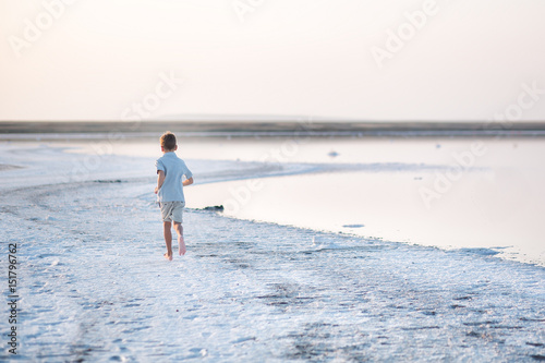 A boy walks along the shore of the lake. A Salt lake shore. A Salt Lake.
