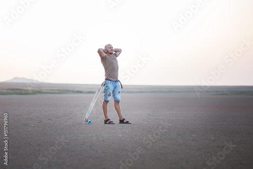 A man walks along the shore of the lake with skate board. A Salt lake shore. A Salt Lake. photo