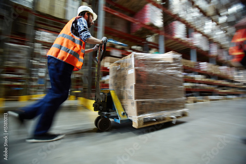 Warehouse worker pushing forklift at work © pressmaster
