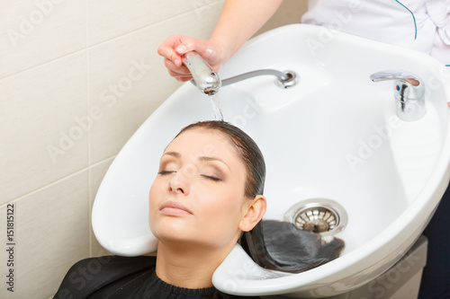 Hairdresser washing her woman customer hair