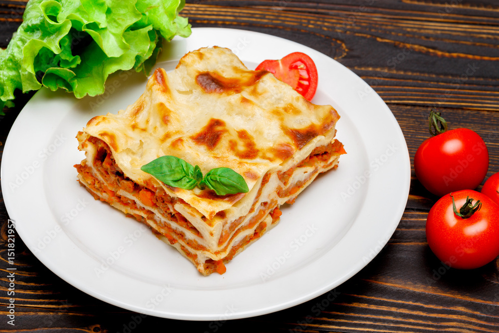 Portion of tasty lasagna on wooden backgound Portion of tasty lasagna on wooden backgound