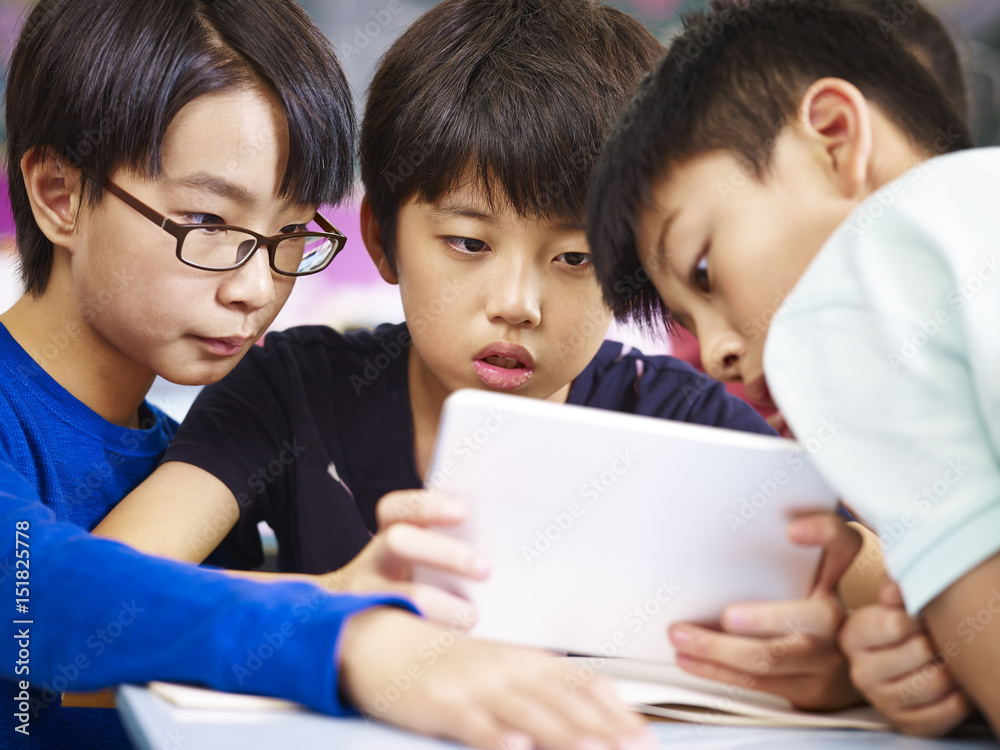 asian elementary schoolboys using tablet together asian elementary schoolboys using tablet together