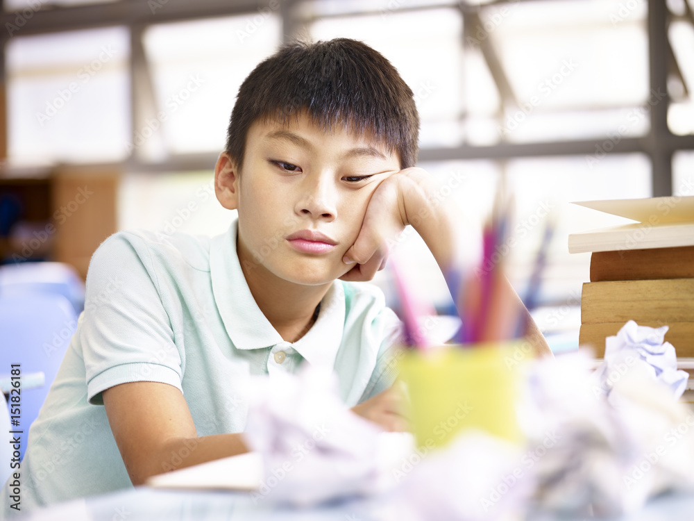 sad schoolchild sitting alone in classroom sad schoolchild sitting alone in classroom