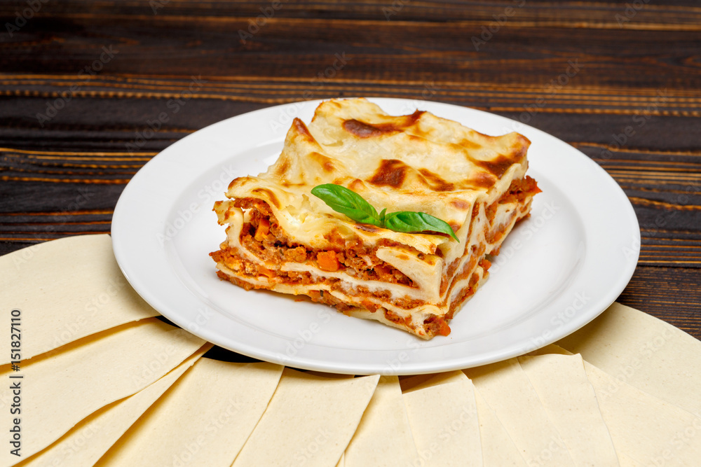 Portion of tasty lasagna on wooden backgound Portion of tasty lasagna on wooden backgound