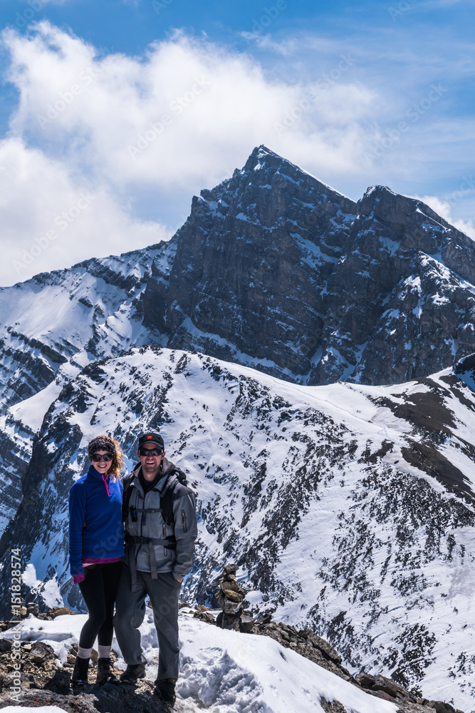 hiking couple on top of mountains with snow and peak in the ackground