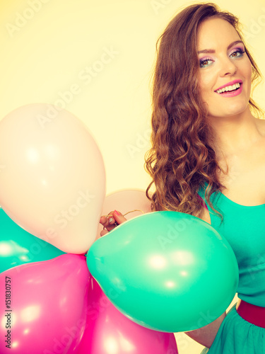 Woman holding bunch of colorful balloons