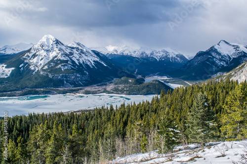 Canadian winter mountain scene with valley, trees, and melting lake