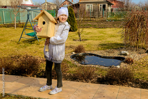 The girl is holding a birdhouse for birds in the spring