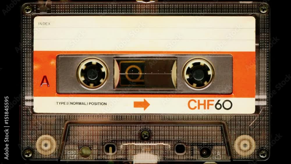 Audio cassette tape in use sound recording in the tape recorder. Vintage music cassette with a blank white label, playing back in the player. 4K, static camera shot