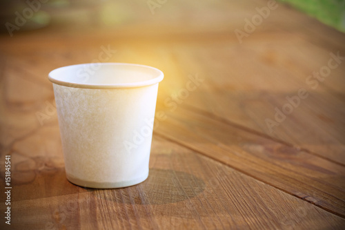 paper cup on wooden table with sunshine and natural background