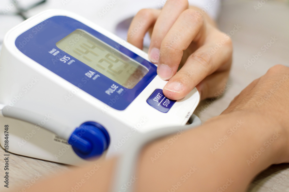 Digital Blood Pressure Monitor. Concept of female press start button on blood pressure.(focus of press start button) Digital Blood Pressure Monitor. Concept of female press start button on blood pressure.(focus of press start button)