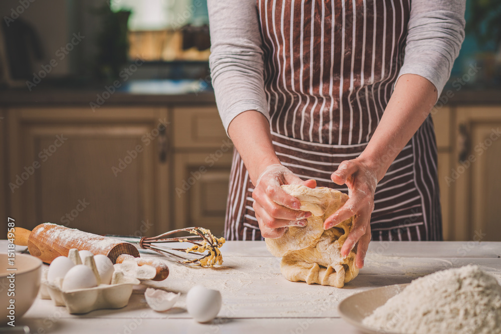 Woman hands kneading dough on kitchen table