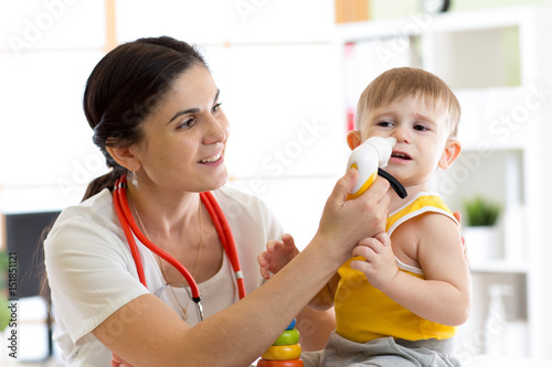 Papier peint Female doctor pediatrician using nasal aspiration for child