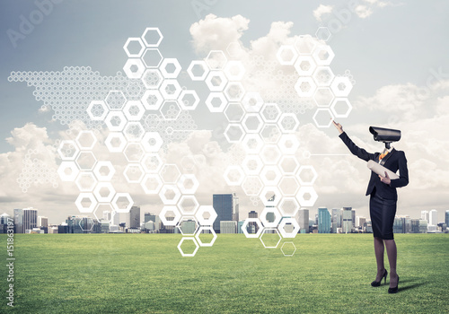 Camera headed woman standing on green grass against modern citys