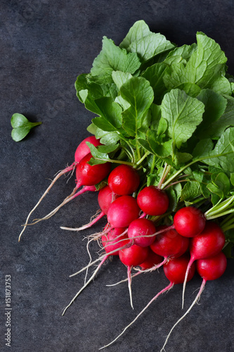 Food background. Fresh, young radish with greens on a black background. Bio food.