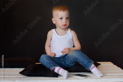 one little boy in house sitting on the floor with mobile phone on a black background